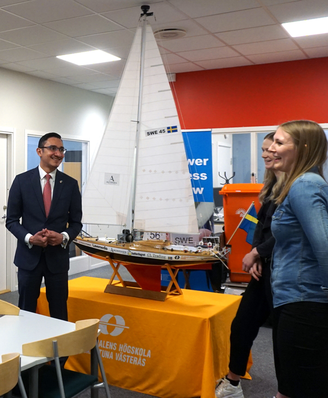 Panama's ambassador to Sweden stands together with students in front of a miniature of a sailing boat. 