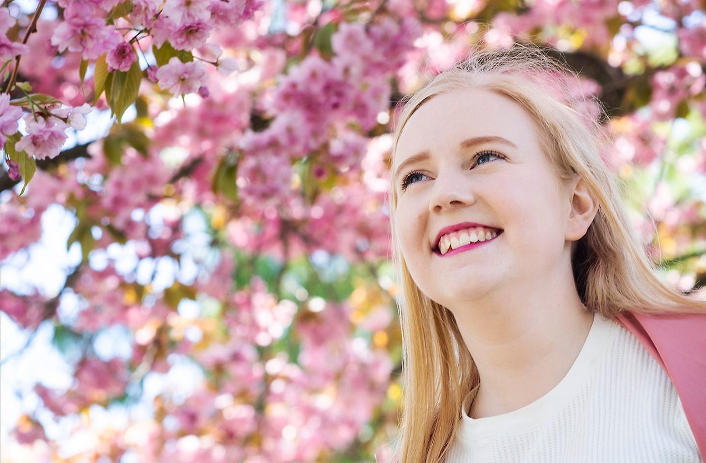 Kvinnlig student framför blommande körsbärsträd