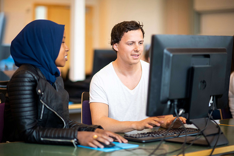 Två studenter sitter vid en dator