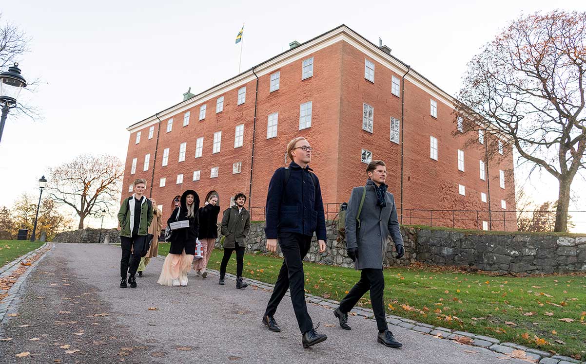 Sju personer går på en grusgång nedanför Västerås slott.