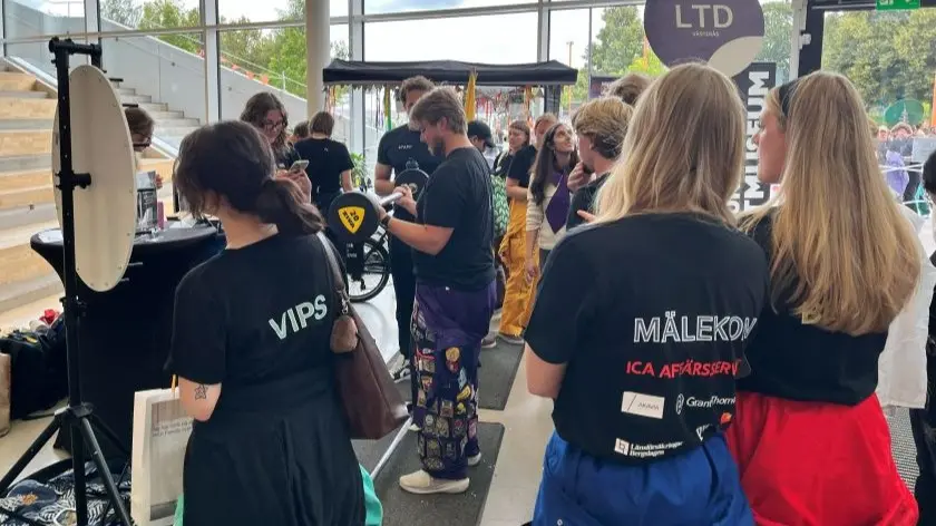 En person står och lyfter vikter medan många står och tittar på.