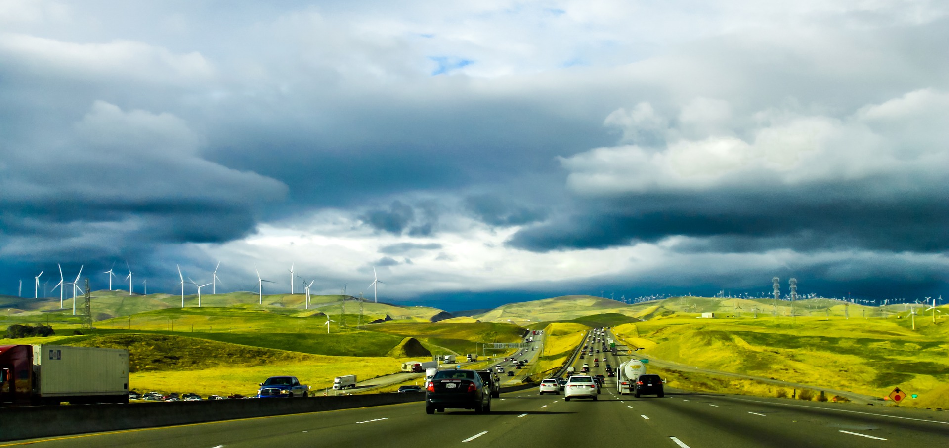 Tungt trafikerad väg i grönt landskap omgivet av vindkraftverk