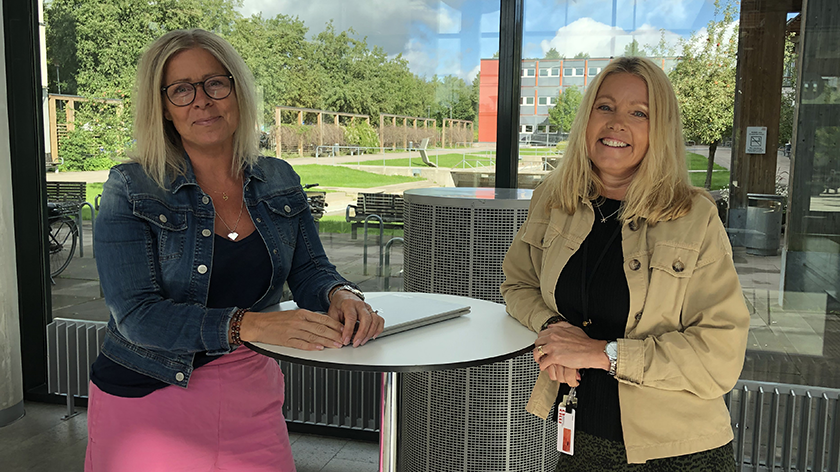 Foto på två kvinnor som står på campus Västerås och ler in i kameran.