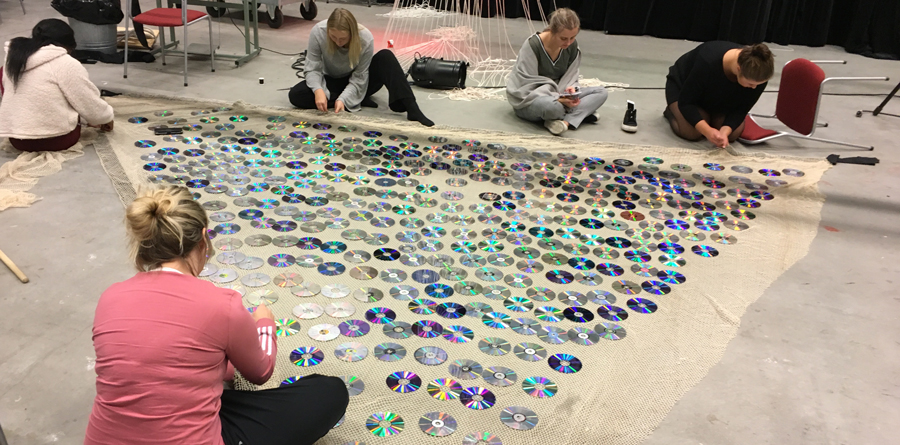 Personer på golvet framför en matta med CD-skivor.